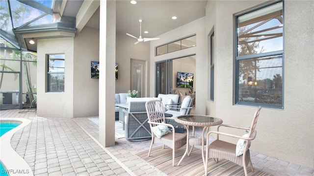 view of patio featuring glass enclosure, ceiling fan, and an outdoor hangout area