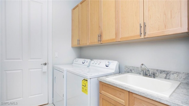 clothes washing area with cabinets, sink, and washer and dryer