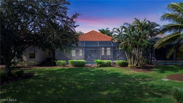 view of front of property featuring a lawn and a lanai