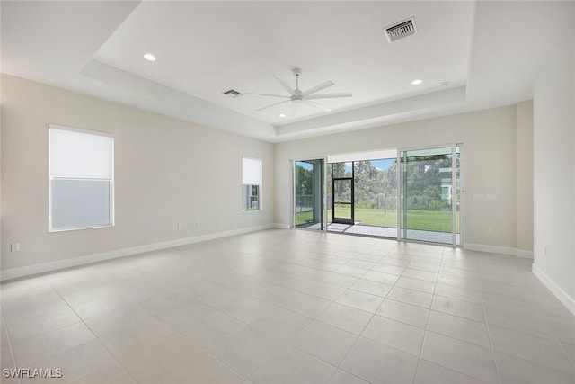 tiled spare room with a tray ceiling and ceiling fan