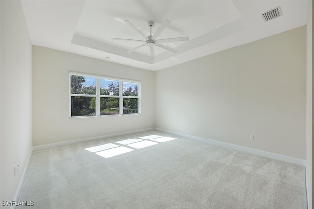 carpeted spare room with ceiling fan and a tray ceiling