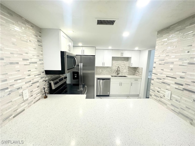 kitchen featuring backsplash, stainless steel appliances, sink, and white cabinets