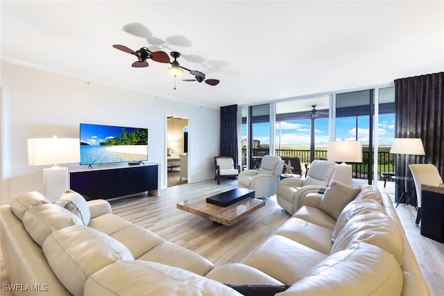 living room with light hardwood / wood-style floors, a wall of windows, ornamental molding, and ceiling fan