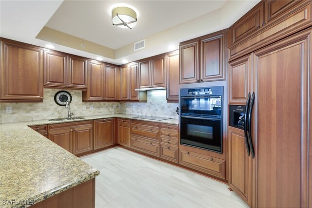 kitchen with light stone countertops, backsplash, black appliances, and sink