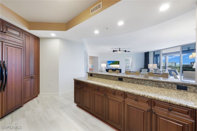 kitchen with light stone countertops, paneled refrigerator, and ceiling fan