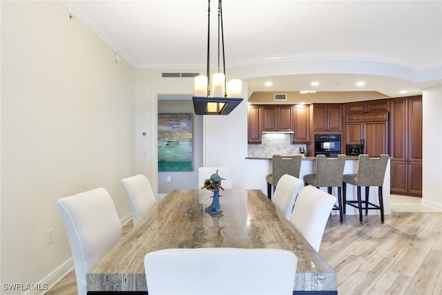 dining area with crown molding and light hardwood / wood-style flooring