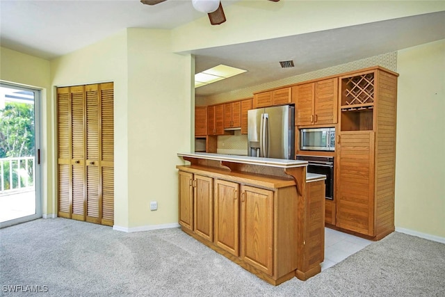 kitchen featuring light carpet, appliances with stainless steel finishes, kitchen peninsula, and ceiling fan