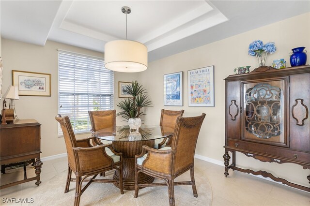 tiled dining space with a raised ceiling