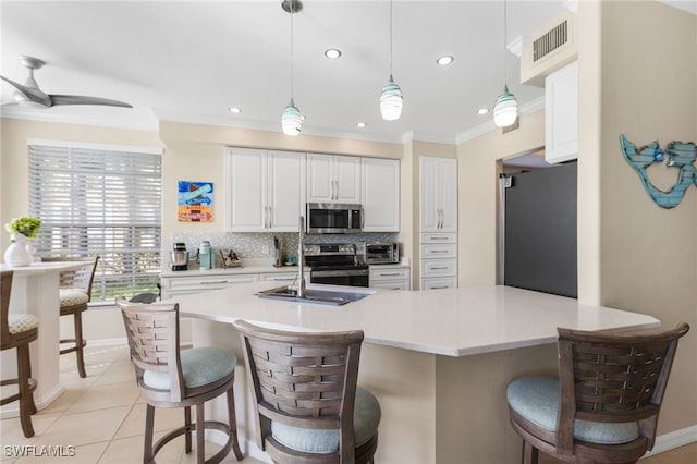 kitchen featuring appliances with stainless steel finishes, pendant lighting, white cabinetry, and decorative backsplash