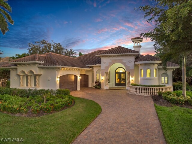 mediterranean / spanish home featuring a yard and a garage