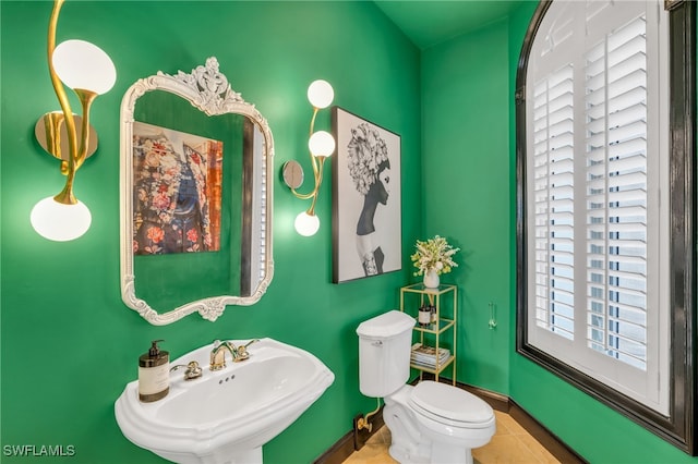 bathroom with toilet, sink, and tile patterned flooring