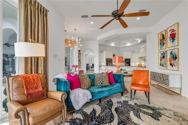 living room with light tile patterned flooring and ceiling fan with notable chandelier