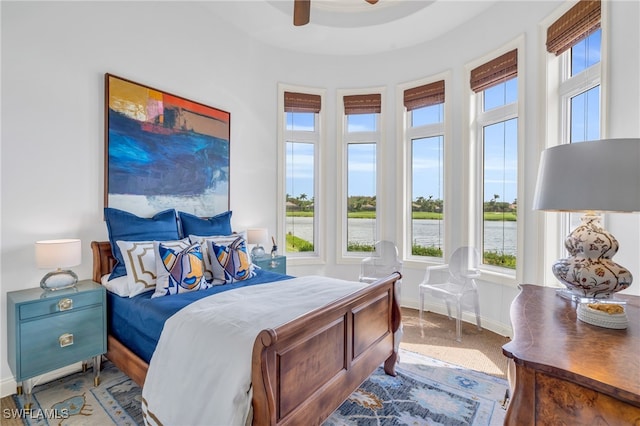 carpeted bedroom featuring a water view and ceiling fan