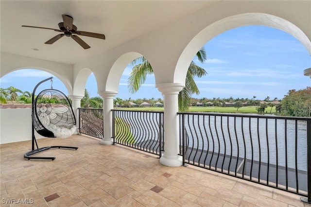 view of patio featuring ceiling fan, a water view, and a balcony