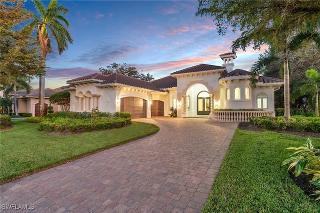 mediterranean / spanish house with a lawn and a garage