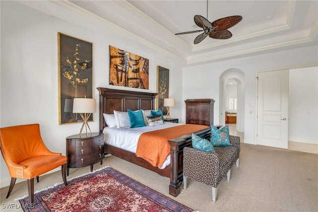 bedroom featuring ceiling fan, crown molding, carpet, and a tray ceiling