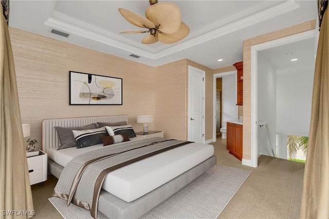 carpeted bedroom featuring connected bathroom, a tray ceiling, and ceiling fan