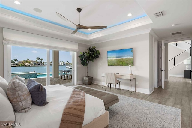 bedroom featuring light hardwood / wood-style flooring, access to exterior, a tray ceiling, and ceiling fan