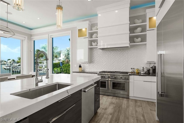 kitchen with white cabinets, light wood-type flooring, decorative light fixtures, premium appliances, and a water view