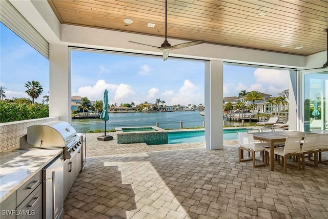 view of patio / terrace with an outdoor kitchen, area for grilling, a water view, and a pool with hot tub