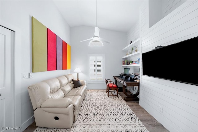 living room with built in shelves, hardwood / wood-style flooring, ceiling fan, and lofted ceiling