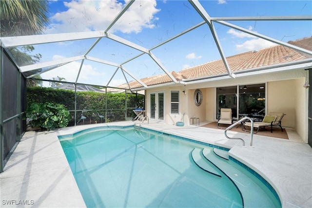 view of pool with glass enclosure and a patio area