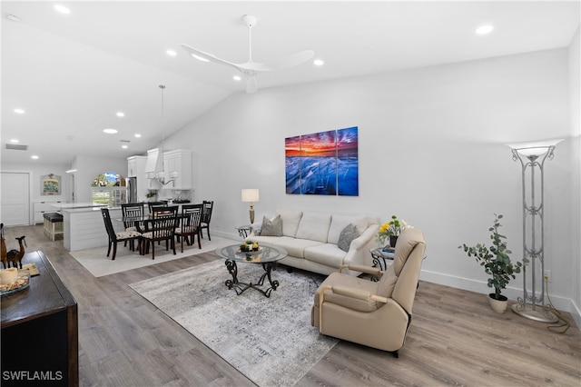 living room featuring ceiling fan, high vaulted ceiling, and light wood-type flooring