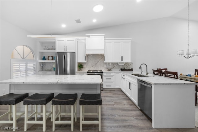 kitchen with appliances with stainless steel finishes, white cabinets, premium range hood, hanging light fixtures, and sink