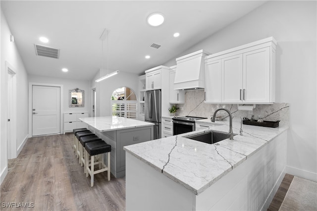 kitchen featuring white cabinets, sink, kitchen peninsula, stainless steel appliances, and lofted ceiling