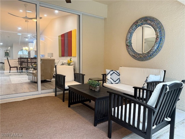 living room featuring ceiling fan with notable chandelier and carpet flooring