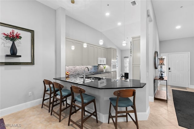 kitchen with white appliances, sink, kitchen peninsula, lofted ceiling, and decorative light fixtures