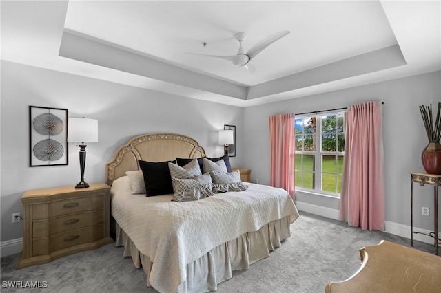 bedroom featuring a raised ceiling, light colored carpet, and ceiling fan