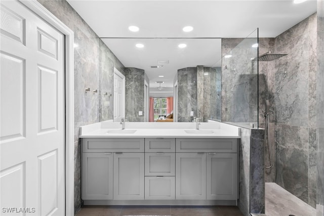 bathroom featuring tile walls, vanity, a tile shower, and tile patterned flooring