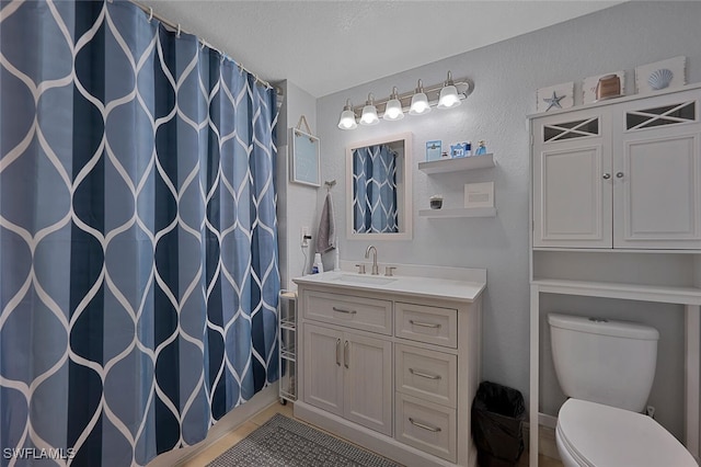 bathroom featuring a textured ceiling, toilet, tile patterned floors, walk in shower, and vanity