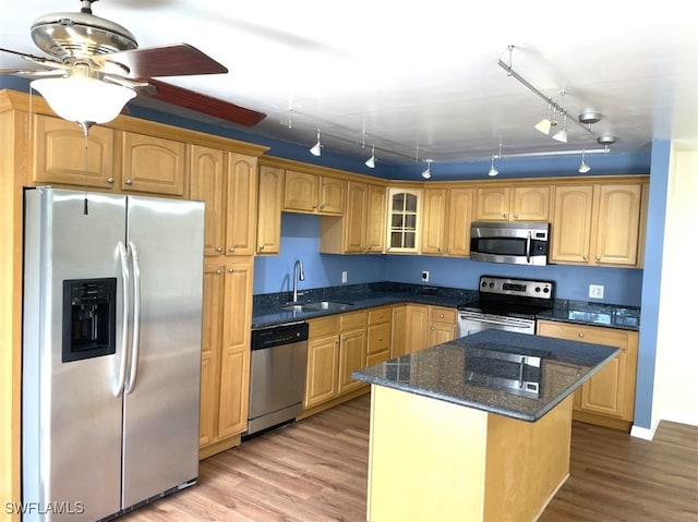 kitchen with track lighting, a kitchen island, appliances with stainless steel finishes, light hardwood / wood-style floors, and sink