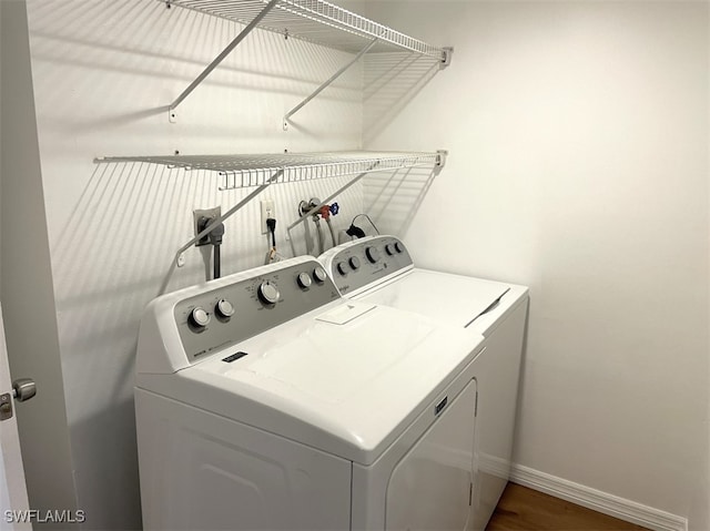 clothes washing area with washer and clothes dryer and dark hardwood / wood-style flooring