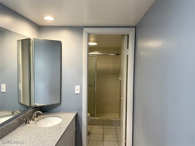 bathroom featuring toilet, tile patterned flooring, vanity, and a shower with door