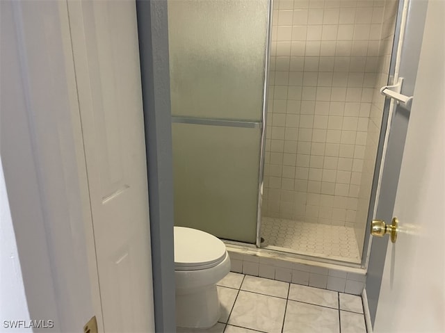 bathroom with toilet, tile patterned floors, and a shower with door