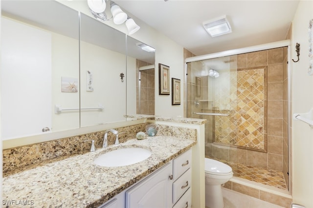 bathroom with vanity, a shower with shower door, and toilet