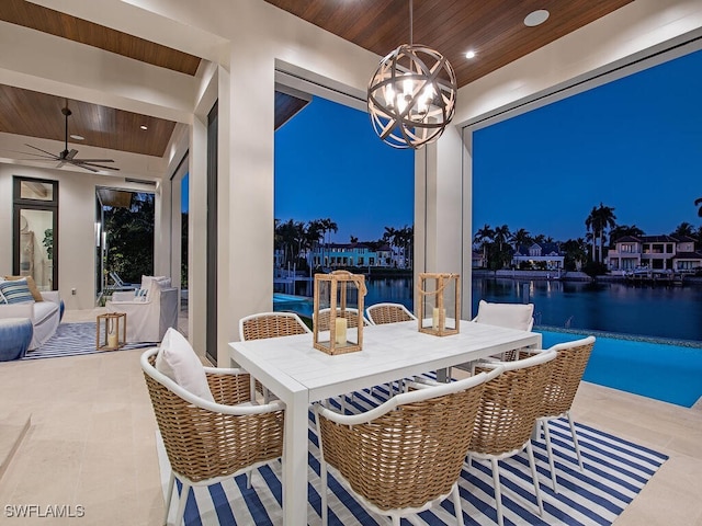 patio at night with a water view and ceiling fan