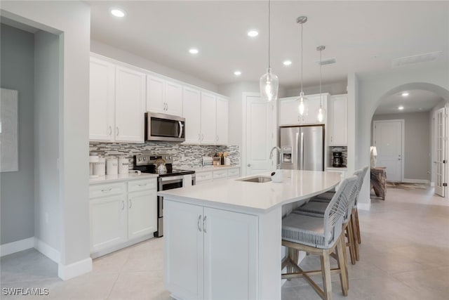 kitchen featuring appliances with stainless steel finishes, a kitchen island with sink, sink, pendant lighting, and white cabinetry