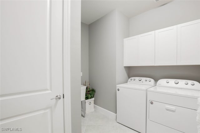 laundry area featuring light tile patterned flooring, cabinets, and washing machine and clothes dryer