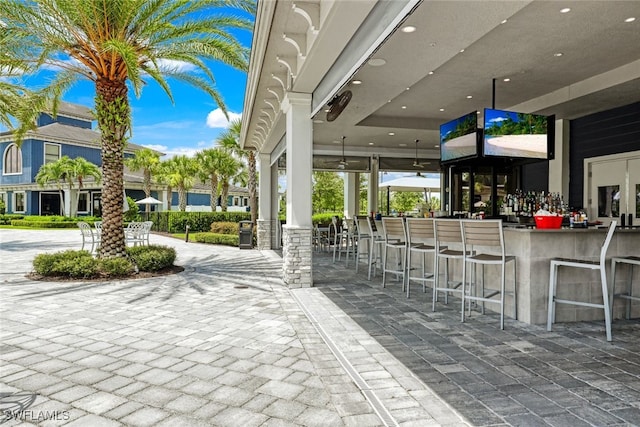 view of patio featuring ceiling fan and exterior bar