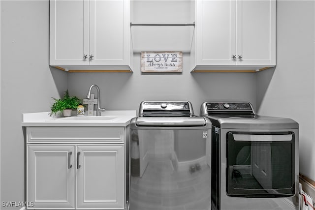 laundry room featuring washer and dryer, sink, and cabinets