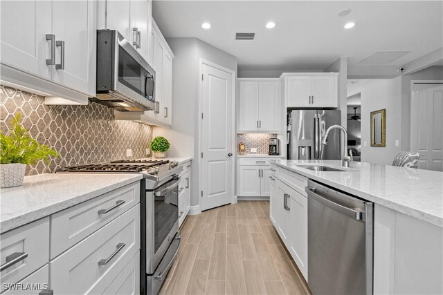 kitchen with light stone counters, white cabinets, and stainless steel appliances