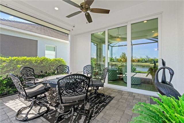 sunroom featuring ceiling fan, a wealth of natural light, and a water view