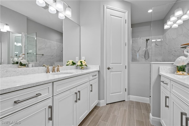 bathroom with a tile shower and vanity