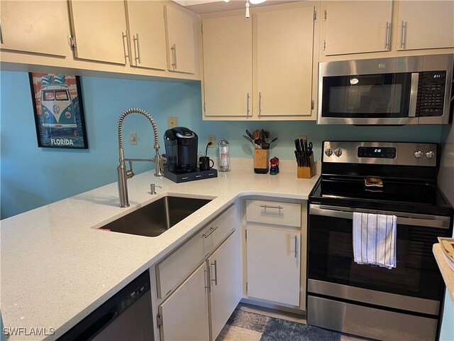 kitchen with stainless steel appliances, white cabinetry, and sink