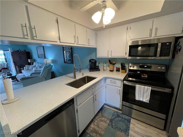 kitchen with sink, white cabinetry, appliances with stainless steel finishes, hardwood / wood-style flooring, and ceiling fan