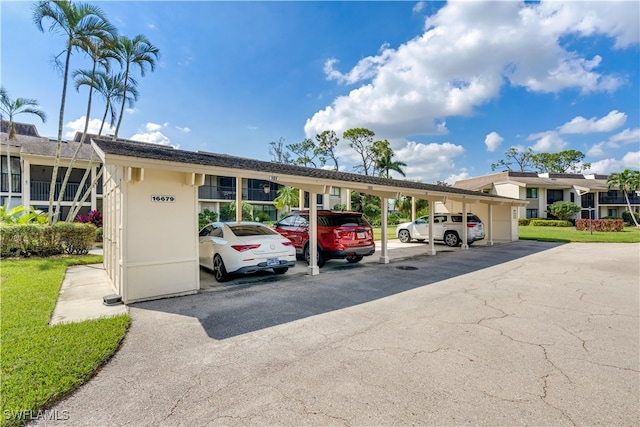 view of parking / parking lot featuring a yard and a carport